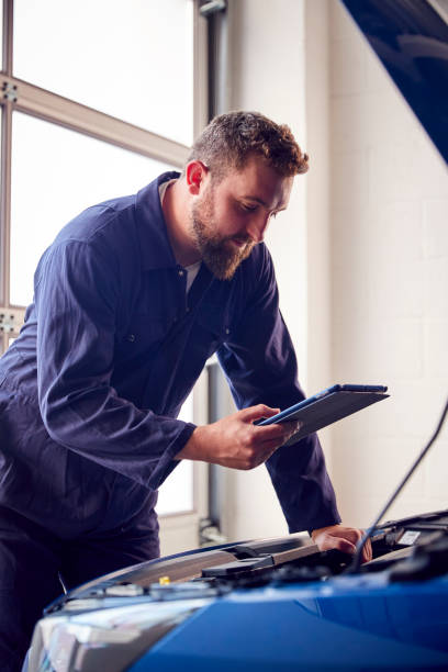 istock Male Mechanic In Garage Using Diagnostic Software On Digital Tablet To Service Car Engine 1409460301
