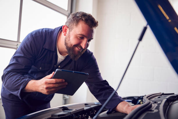 istock Male Mechanic In Garage Using Diagnostic Software On Digital Tablet To Service Car Engine 1409460431