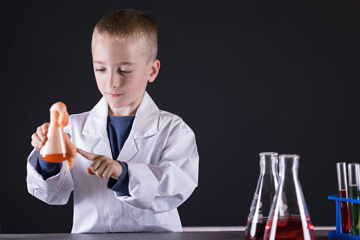 Seven year old wearing a white lab coat experimenting with chemicals.