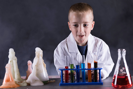 Seven year old wearing a white lab coat conducting a disastrous chemistry experiment.