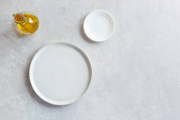 White empty serving dish, small plate and olive oil pitcher, top view