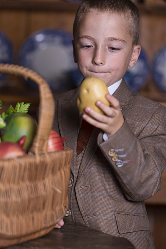 A handsome 4 year old boy in a striped blue T-shirt eats an apple on a white background, space for text, long banner