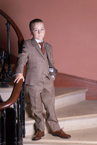 Seven-year-old boy on the stairs wearing a three piece suit.