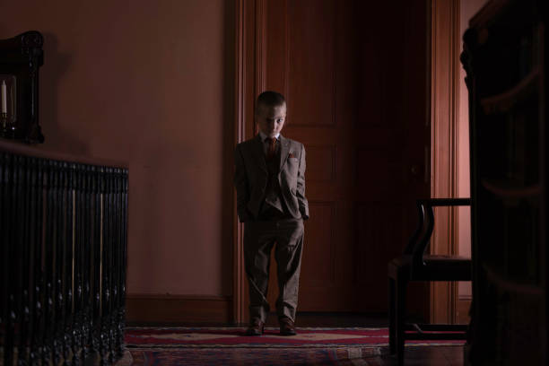 Funny old fashioned cinema film projectionist. The boy is playing in with the 16 mm film projector. He is tangled in a celluloid film. Studio shooting, black and white image