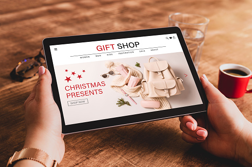 Buying Christmas presents (fashion accessories) online - internet gift shop. Tablet in womanâs hands. Made up illustrative e-commerce content design.