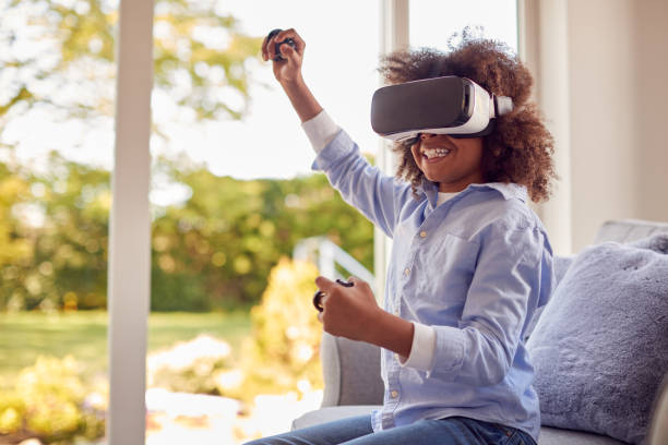 istock Boy Sitting On Sofa In Lounge Wearing VR Headset Playing Game 1409463154