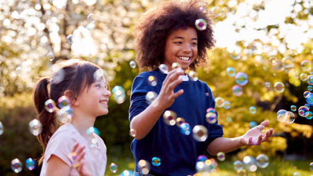 istock Smiling Boy And Girl Outdoors Having Fun Playing With Bubbles In Garden 1409463288