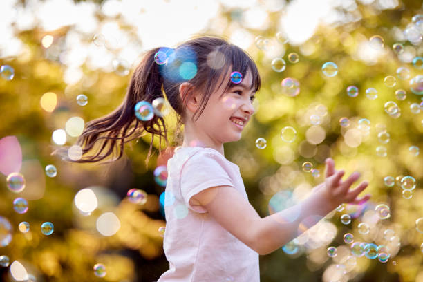 istock Smiling Girl Outdoors Having Fun Playing With Bubbles In Garden 1409463322