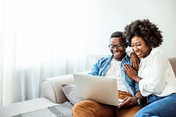 Photo of Attractive couple using laptop together on sofa to shop online at home