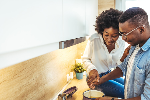 Affectionate couple preparing lunch in a domestic kitchen. Young couple in love in the kitchen. Happy couple standing in kitchen at home preparing together yummy dinner on first dating