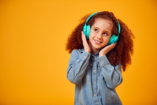 Foto de estudio de una joven sonriente escuchando música en auriculares sobre fondo amarillo photo
