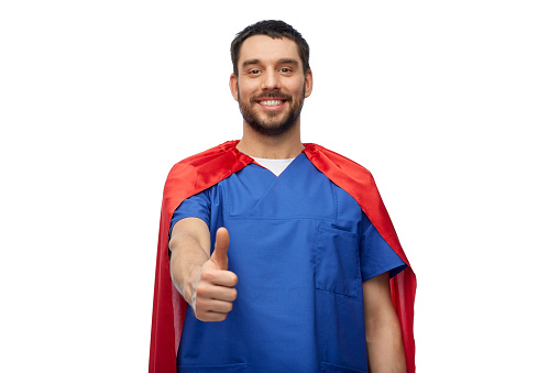 healthcare, profession and medicine concept - happy smiling doctor or male nurse in blue uniform and red superhero cape showing thumbs up over white background