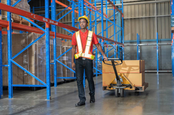 istock Worker pulling hand pallet truck distribute goods in large warehouse surrounding with high level of warehouse racking 1409465708