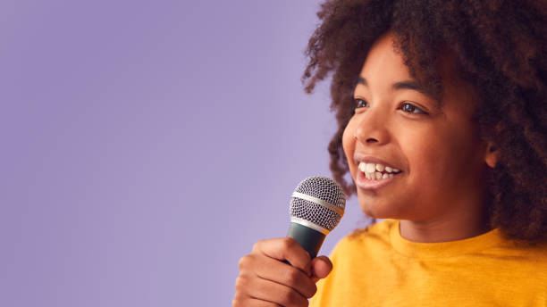 istock Studio Shot Of Boy Singing Karaoke Into Microphone Against Purple Background 1409466078