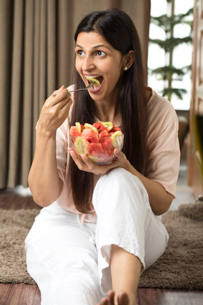 donna felice che mangia fette di frutta fresca - salad fruit freshness dessert foto e immagini stock