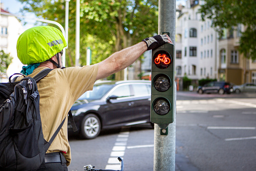 Middle-aged male cyclist waiting at red traffic light on a street in the city center.