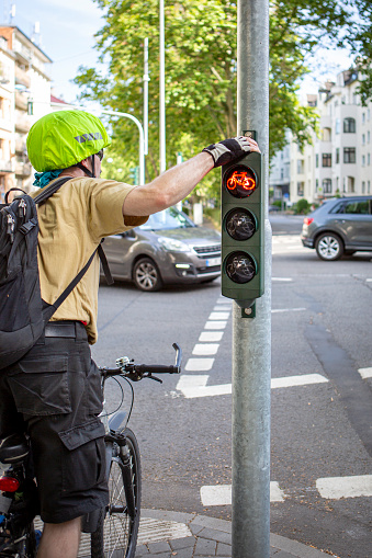 Middle-aged male cyclist waiting at red traffic light on a street in the city center.