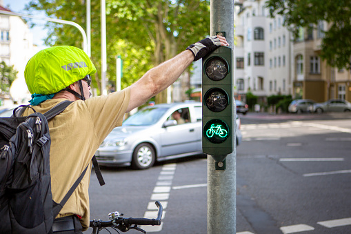 Middle-aged male cyclist waiting at traffic light on a street in the city center.