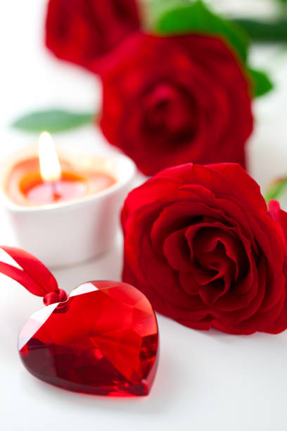 red roses with burning candles on red background
