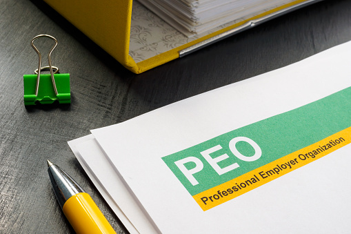 Papers about PEO professional employer organization and yellow folder.