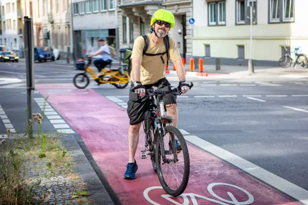 Male cyclist waiting on a bicycle lane in front of a stoplight