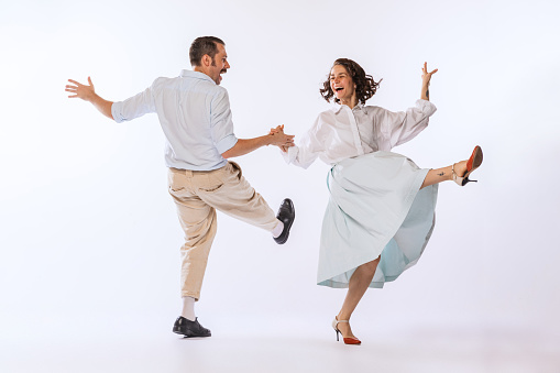Portrait of young beautiful couple, man and woman, dancing retro dance isolated on white studio background. Enjoyment. Concept of vintage fashion, hobby, activity, art, music, party, creativity and ad