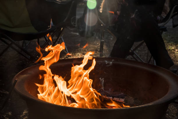 Campfire burning in a firepit . People sitting around. Camping life. Outdoor family recreation.