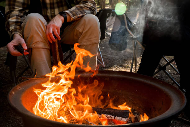 campfire burning in a firepit . people sitting around. camping life. outdoor recreation. - fire pit campfire bonfire fire imagens e fotografias de stock