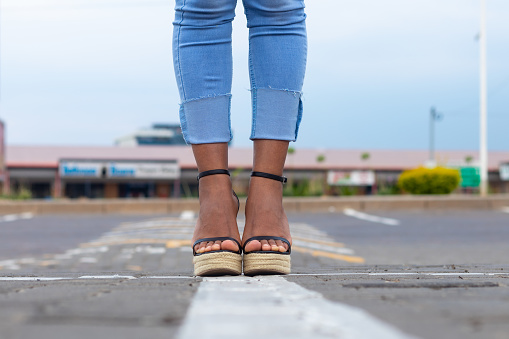 Woman pedestrian on tiled street, cobblestones and high heels
