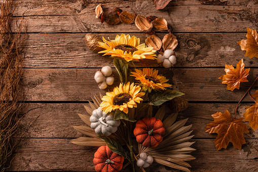 Autumn background decoration from dry leaves, cotton, pumpkin and sunflower on dark wooden background top view with copy space for autumn, fall, thanksgiving concept