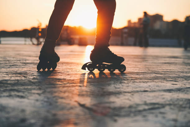 Sunset rollerblade silhouette Closeup of Rollerblader at a park at sunset time with blurred people at background inline skating stock pictures, royalty-free photos & images