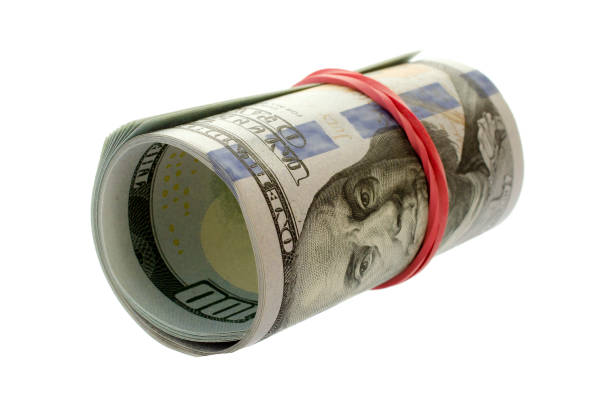 istock Dollar roll wrapped with red ribbon. 100 dollar bills on a roll isolated on white background. Rolled up money isolated on white background. Dollars isolated on white background. 1409479757