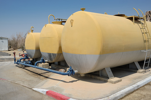 Horizontal cylindrical storage tank container for water liquid. Fire hydrant with Yellow and gray colored Outdoor Water tank on Fuel station