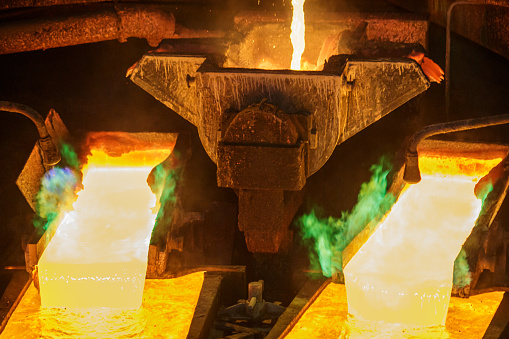 Hot liquid copper pouring into molds. Green flame from molten metal. Anode casting machine.
