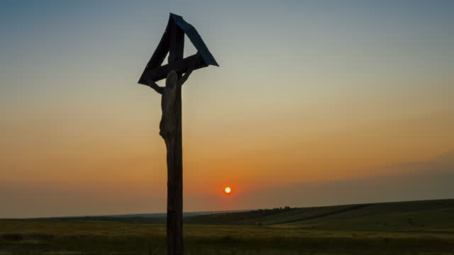 A Christian Cross on the field at sunrise - tilt up