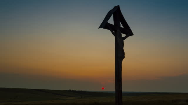 A Christian Cross on the field at sunset - pan shot