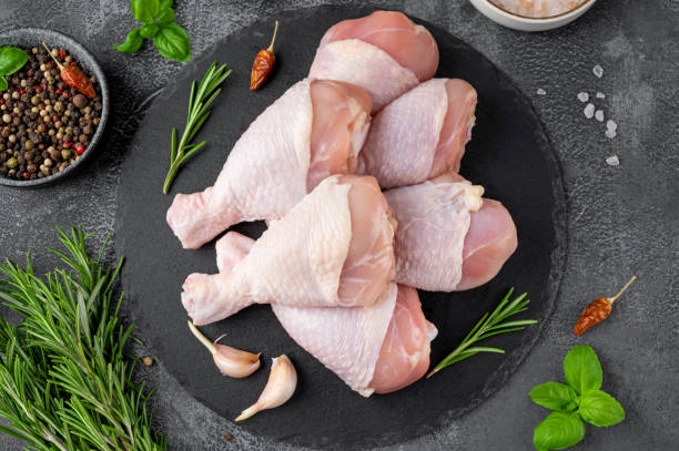 istock Raw uncooked chicken legs on a dark slate on a dark concrete background. Meat with ingredients for cooking. Top view. 1409488287