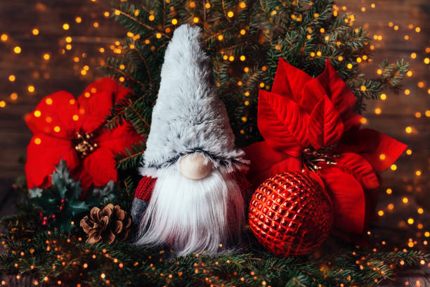 Christmas composition with gnome and festive decorations on wooden background.