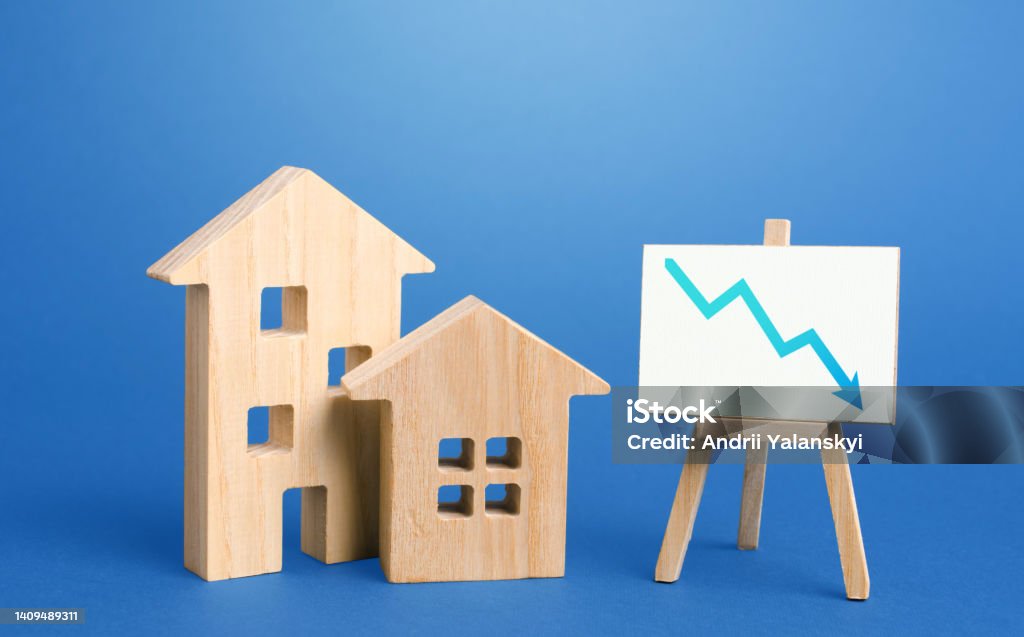 Figurines of houses and down arrow chart negative trend easel. Big promotions and discounts on home sales. Special purchase offers. Low demand for real estate and housing, economic downturn recession. Consumerism Stock Photo