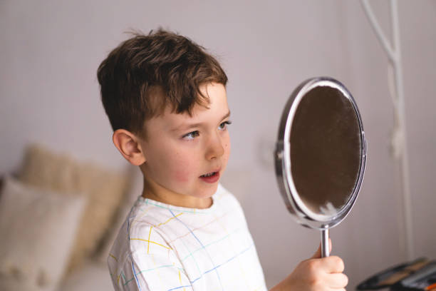 istock Cute little boy pronouncing sound O looking at mirror doing an online Speech therapy lesson through a laptop 1409489667