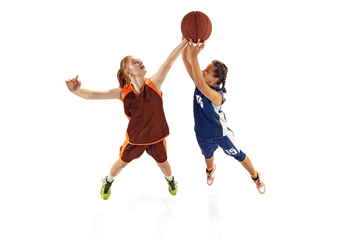 Play defense. Female basketball players, young girls, teen training with basketball ball isolated on white background. Concept of sport, team, enegry, skills. Junior game. Copy space for ad, text