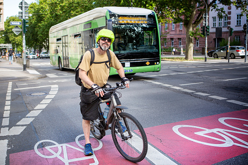Male cyclist standing on a bike lane in the city center. Some unrecognisable traffic in the background.