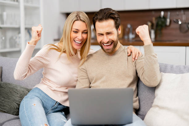 istock Yeah. Cheerful guy got a promotion at work, won the lottery, bought a vacation ticket, sitting at laptop. Caucasian woman and her man in front of laptop 1409491548