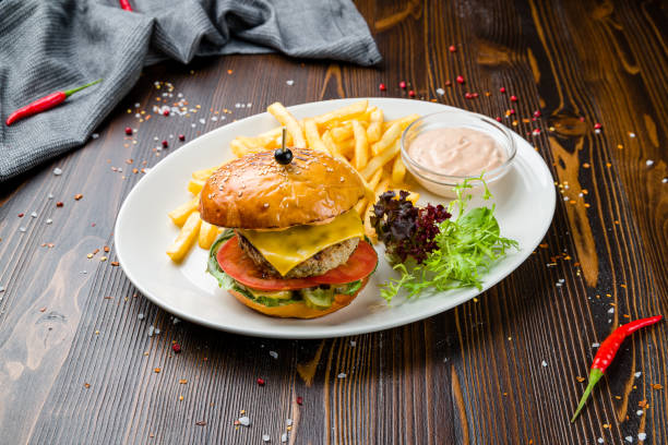 istock Burger with meat patty, cheese and vegetables on wooden table 1409494493