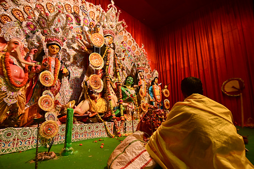 Howrah, India -October 13, 2021 : Hindu Priest worshipping Goddess Durga. Ashtami puja aarati - sacred Durga Puja ritual - shot at night.