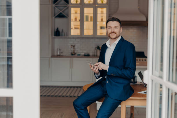 istock Bearded guy entrepreneur in suit using modern gadgets in his apartment 1409497871