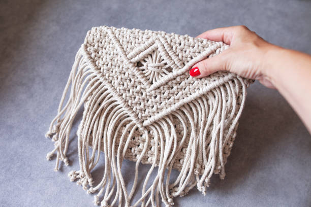 Handmade macrame cotton ross-body bag. Eco bag for women from cotton rope. Scandinavian style bag.  Bejge tones, sustainable fashion accessories. Details. Close up image stock photo