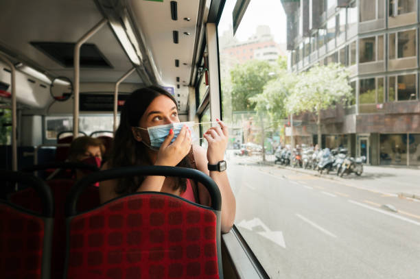 istock woman putting on a face mask in a bus 1409499715