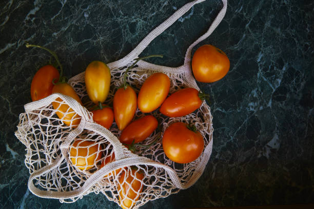 istock Harvest bright colourful tomatoes in eco shopping bag with reflection background. Zero waste. Eco shopping. Copy space. 1409500414