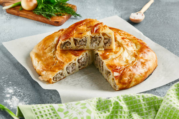 Classic turkish pie with meat on wooden board. Composition with burek pie on concrete background with textile and spices. Balkan pie with minced meat  in rustic style on gray table. Classic turkish pie with meat on wooden board. Composition with burek pie on concrete background with textile and spices. Balkan pie with minced meat  in rustic style on gray table balkans stock pictures, royalty-free photos & images